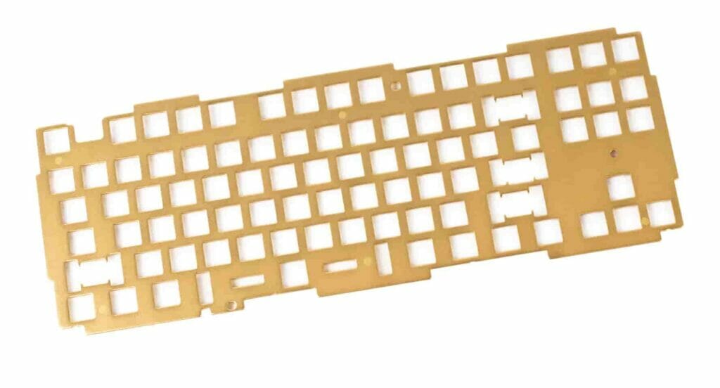 A gold keyboard plate made of anodized aluminum. The plate has a standard ANSI layout and supports Costar stabilizers.

