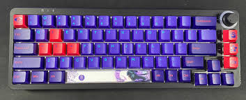 A mechanical keyboard with a purple aluminum case, white and purple keycaps, and clear mechanical switches with green stems.

