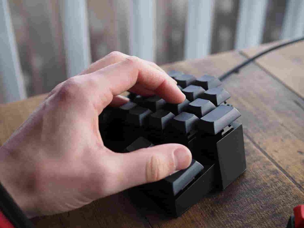 A person typing on a black and red Corne keyboard.


